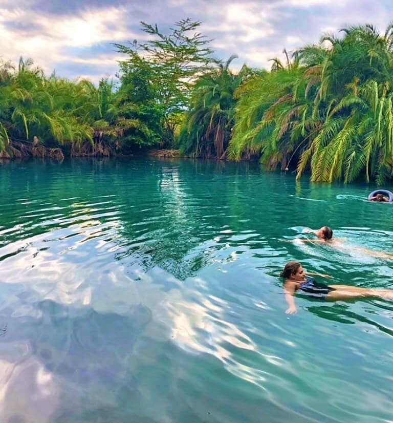 Turquoise waters of Rundugai Hot Springs surrounded by palm trees