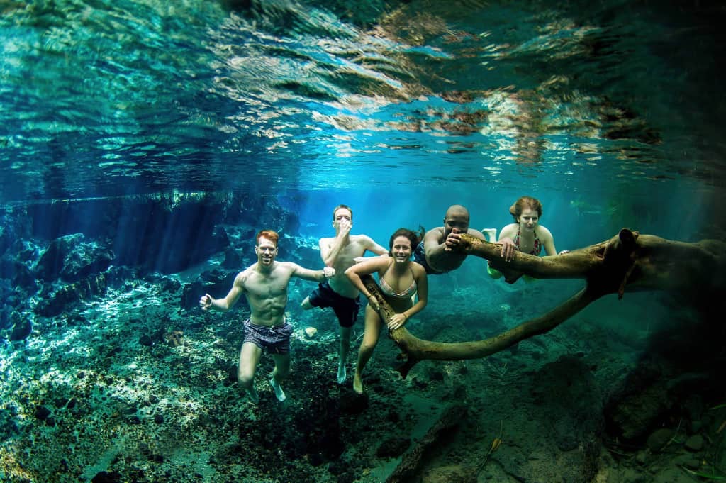 Underwater view of swimmers in the crystal-clear waters of Rundugai Hot Springs